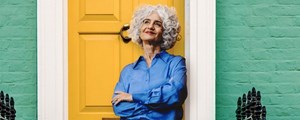 Lady leaning against a yellow  exterior house door of