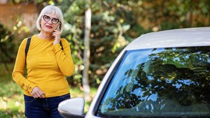 woman next to a broken down vehicle calling for breakdown support