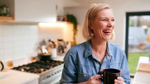 Image of a woman holding a mug standing in the kitchen