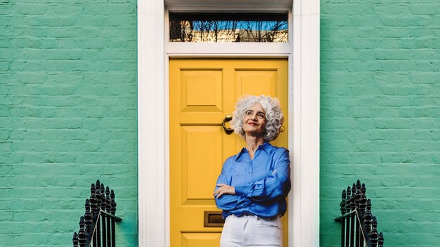 Older lady leaning on yellow front door