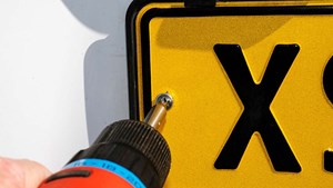 a uk number plate being removed with a screwdriver