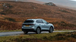 a grey car with a UK licence plate drives on a scenic road