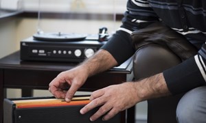 Man going through LPs next to a record player at home
