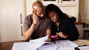 a couple sit at a table and puzzle over documents together