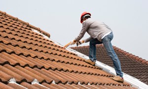 Man on outside of roof, making repairs to a leak.
