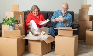 Elderly couple packing during their downsize move, laughing on couch