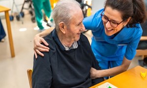senior man being hugged by a nurse