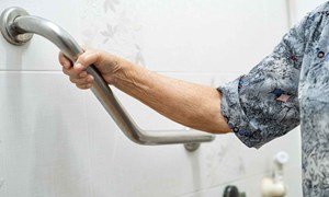 Hand holding onto a metal rail on bathroom wall