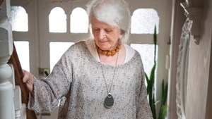 Person wearing personal alarm pendant walking up the stairs at home