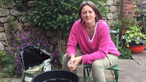 gardening expert alex mitchell sits down in front of a compost barrel