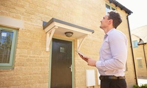 Surveyor standing outside a house surveying the property