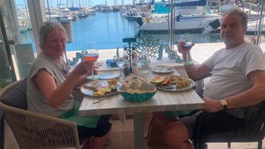 a middle aged couple eating lunch overlooking a harbour