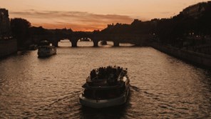 a river cruise boat going under a European bridge at Sunset
