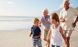 Grandparents and children running along beach