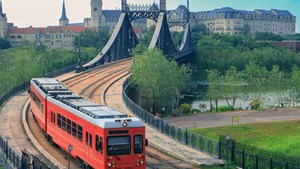a red tram crosses an iron bridge on the european mainland