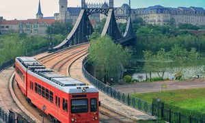 a red tram crosses an iron bridge on the european mainland