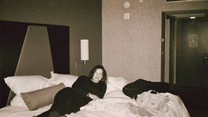 a black and white photo of a woman relaxing on a hotel bed