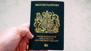 a blue uk passport being held up by a hand