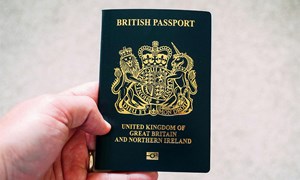 a blue uk passport being held up by a hand