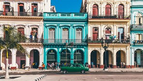 a green sedan parked in front of a colonial facade in Havana Cuba
