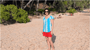middle aged lady standing smiling on a beach with palm trees in the background