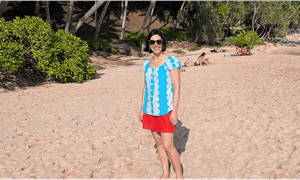 middle aged lady standing smiling on a beach with palm trees in the background